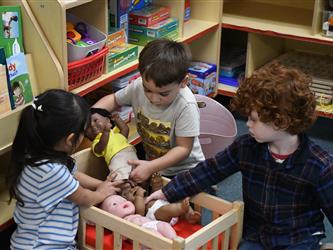 TK students playing with baby dolls